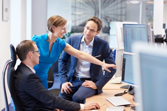 Ein EEX-Team betrachtet die Kurse von CO2-Zertifikaten auf einem Monitor.