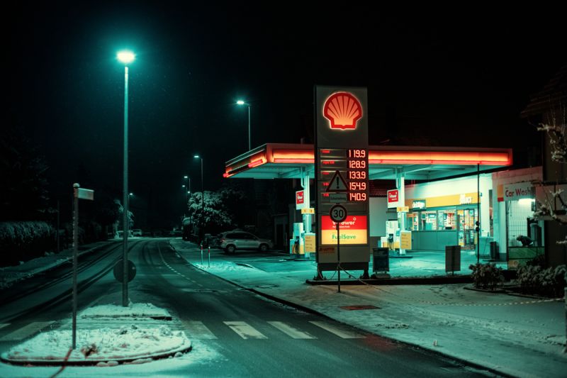 Kleine Shell-Tankstelle bei Nacht, vergleichsweise sparsam beleuchtet, eine Straßenlaterne spendet auch nur wenig Licht.