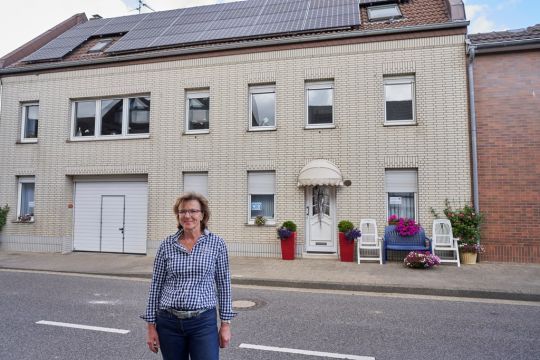 Barbara Ziemann-Oberherr vor ihrem Wohnhaus mit weißen Klinkern in Keyenberg, auf dem Dach die Solaranlage.