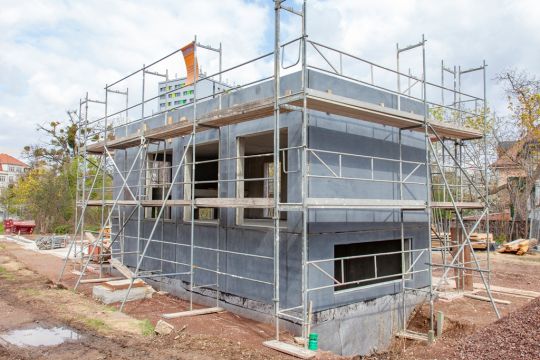 Eingerüsteter kleiner einstöckiger Betonhaus-Rohbau.