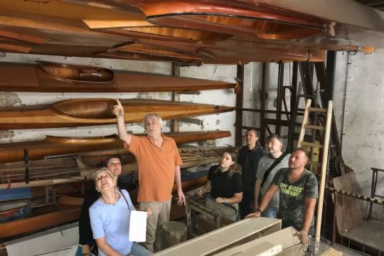 Das Team des Kunstprojekts Keine Handbreit Wasser: Sieben Leute stehen in einem Bootsschuppen.