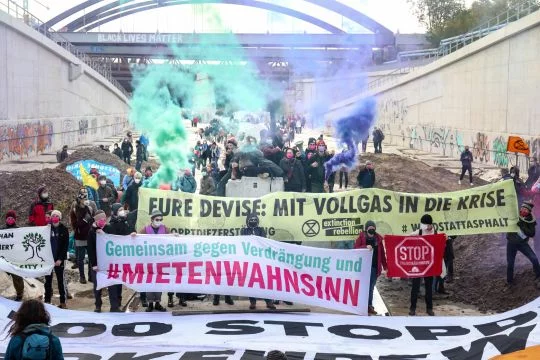 Aktivist:innen stehen mit mehreren Bannern auf der Baustelle der A100