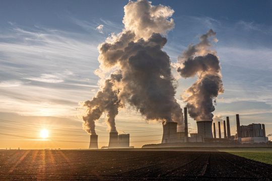 Dampfendes Braunkohlekraftwerk im Sonnenschein.