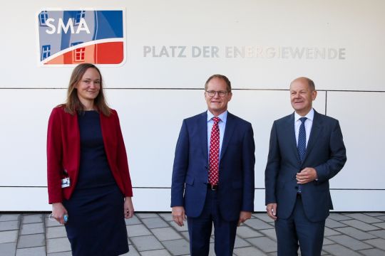 Vizekanzler Olaf Scholz steht mit SMA-Persönlichkeiten auf dem neu eingeweihten Platz der Energiewende.