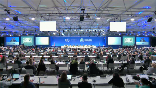Große Halle mit vielen Tischreihen, an denen die Klimagipfel-Delegierten jeweils mit einigem Abstand sitzen, weit vorn das Podium mit der Konferenzpräsidentschaft.