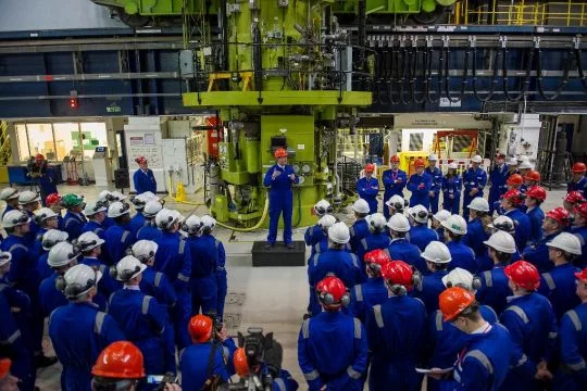 Der britische Regierungschef David Cameron spricht im Oktober 2013 vor Beschäftigten des Atomkraftwerks Hinkley Point, alle sind blau gekleidet und haben rote oder weiße Helme auf.