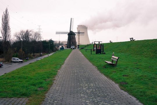 Das Atomkraftwerk Doel in Belgien, vom Deichweg aus betrachtet, hinter einer alten Windmühle stehend.