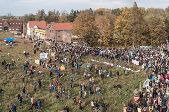 Viele Menschen auf einer Wiese vor dem Dorf Lützerath am Rand des Tagebaus Garzweiler im Rheinischen Braunkohlerevier.