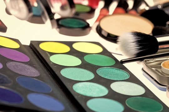 Schminkpalette mit grünen, gelben und anderen Farben für Lidschatten.