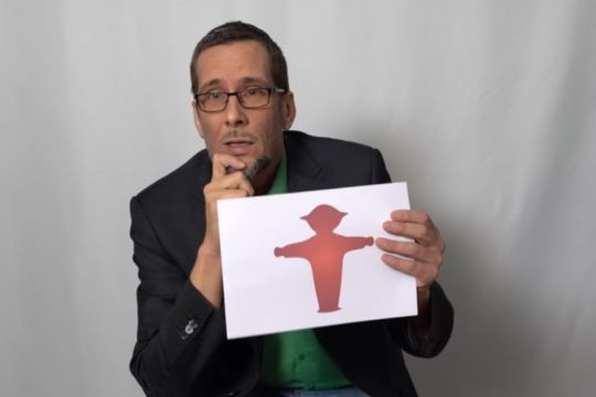 Volker Quaschning hält ein Blatt mit einem roten Ampelmännchen hoch.