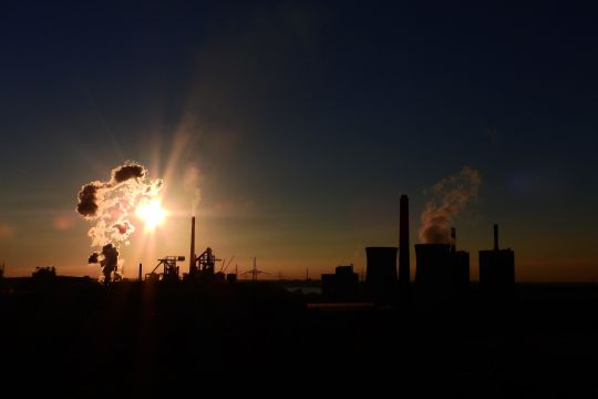 Kohlekraftwerk im Ruhrgebiet mit Kühltürmen und rauchenden Schornsteinen im Abendlicht.