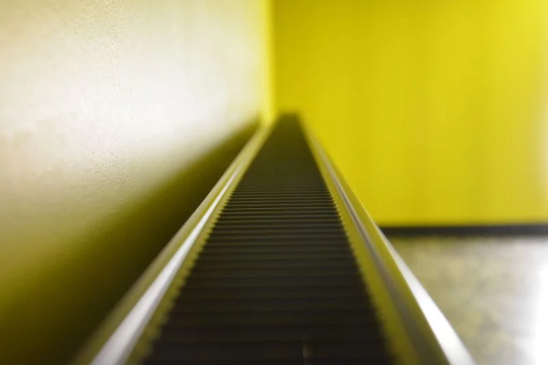 Ein Heizkörper, schräg von der Seite betrachtet, vor einer gelben Wand.