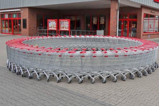 Vor einem Supermarkt sind viele Einkaufswagen ineinandergeschoben und in einem großen Kreis aufgestellt worden.