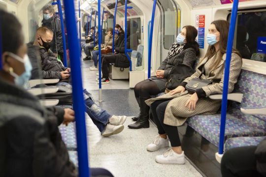 In der U-Bahn sitzen einige Frauen und Männer mit Corona-Masken.