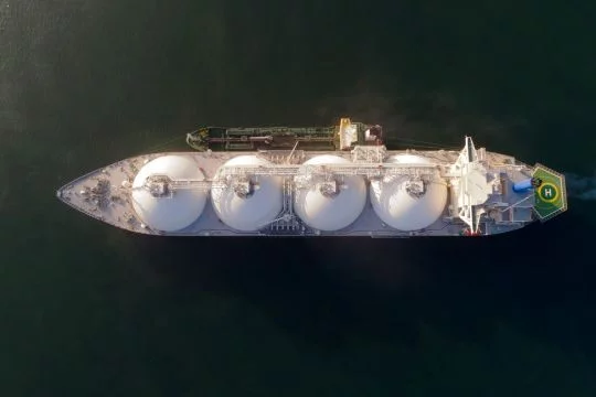 Flüssigerdgas-Tanker mit vier weißen Behältern im dunklen Meer, genau von oben aufgenommen.