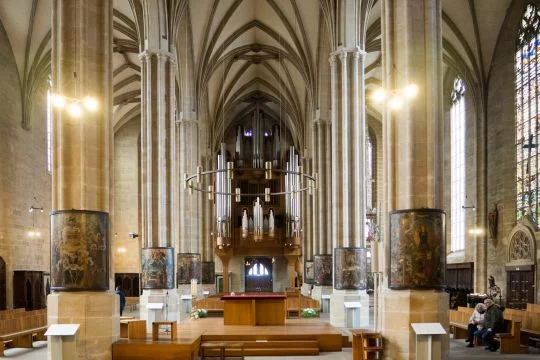 Hohe Kirchenhalle, am Rand sitzen zwei ältere Menschen.