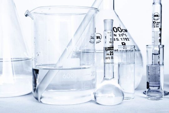 Verschiedenartige Glasbehälter im Chemielabor, etwa zur Hälfte mit einer farblosen Flüssigkeit gefüllt, teils mit schwarz aufgedrucktem Volumen.