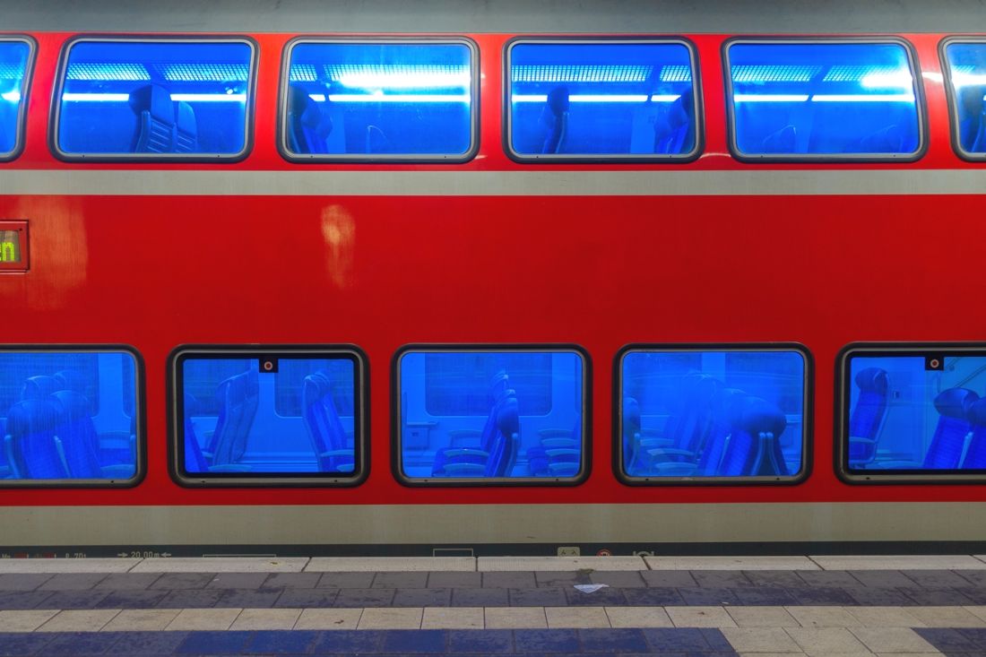 Leerer Regionalzugwagen am nächtlichen Bahnsteig, die fenster leuchten geheimnisvoll blau.