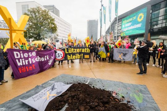 Vor der Bundesdelegiertenkonferenz der Grünen stehen protestierende Menschen mit gelben X-Zeichen und Bannern mit Aufschriften wie: Diese Wirtschaft tötet.