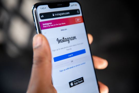 Eine Hand hält ein Smartphone, auf dem die Login-Seite von Instagram angezeigt wird.