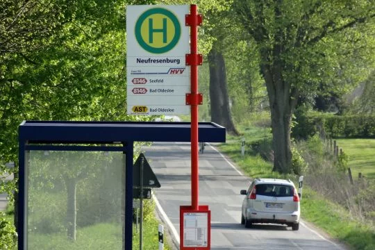 Bushaltestelle an einer Landstraße, ein Auto fährt vorbei.