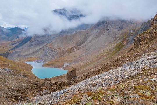 Vegetationslose Berglandschaft mit Geröllfeldern und einem See.