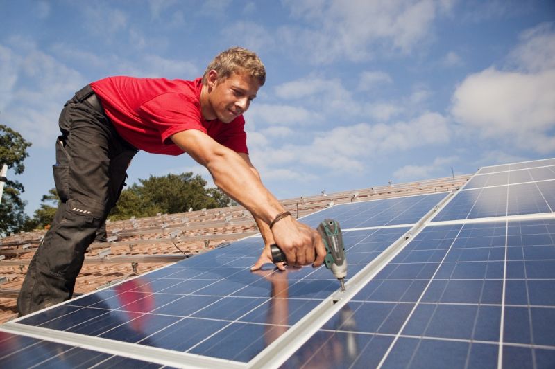 Ein Monteur befestigt ein Solarpaneel mit dem Akkuschrauber.