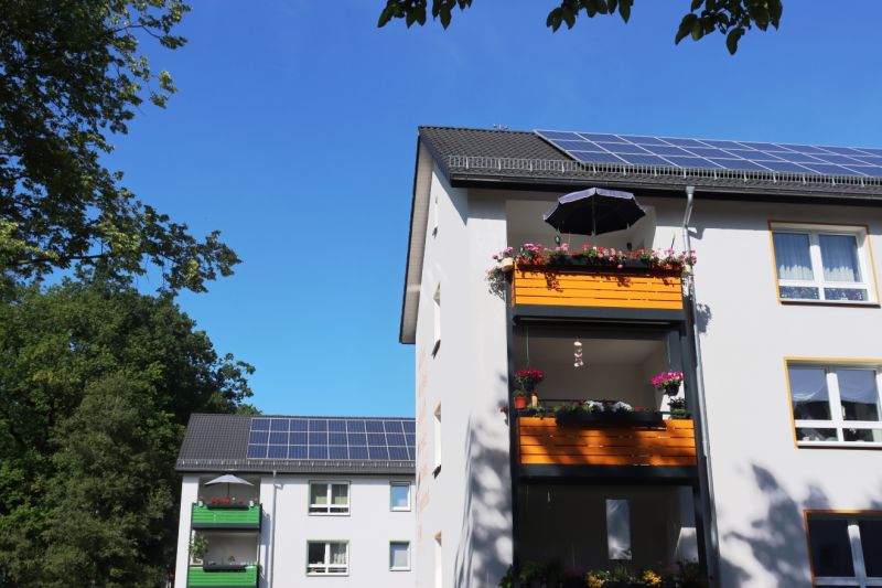 Zwei sanierte Mehrfamilienhäuser des sozialen Wohnungsbaus in Bielefeld mit Solarpaneelen auf dem Dach.