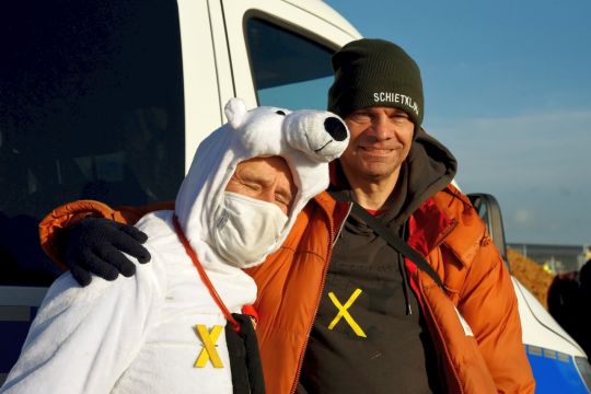 Zwei Aktivisten Arm in Arm, einer hat ein Eisbärenkostüm an, der andere trägt eine Mütze mit der Aufschrift: Schietklima.