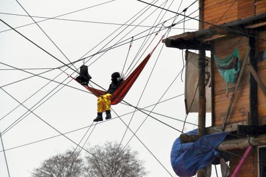 Ein Mensch sitzt in einer Hängematte, die in einem Netz aus zahlreichen Seilen besfestigt ist.