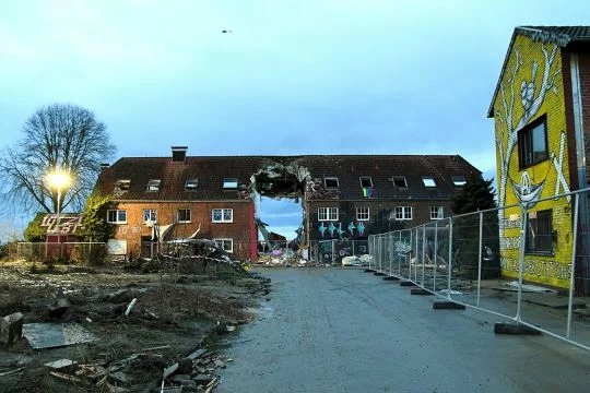 Zweistöckiges Backsteinhaus auf einem ehemaligen Bauernhof, der Teil mit dem Regenbogen-Tor wurde herausgerissen, so dass man durch das Haus hindurchsehen kann.