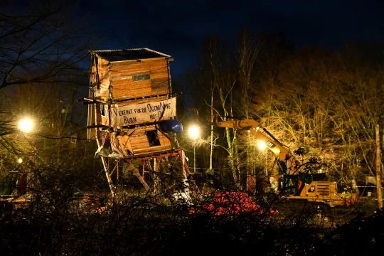 Viereckiger frei stehender Holzturm mit einem Transparent: Vereint für die Ogoni Nine.