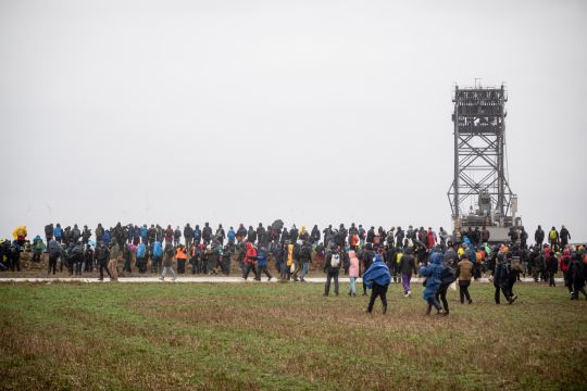 Etwa hundert Menschen stehen an der Abbruchkante des Braunkohletagebaus Garzweiler zwei, der obere Teil eines Baggers ragt aus dem Tagebau hervor.