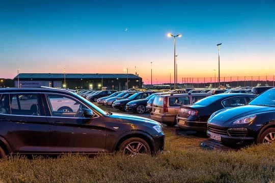 Zahlreiche große, schwarze Autos auf dem Parkplatz am Flughafen Niederrhein in der Abenddämmerung.