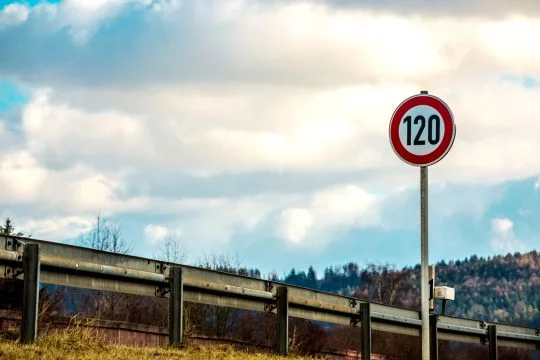 Autobahn-Leitplanke, neben der ein Verkehrsschild die Höchstgeschwindigkeit von 120 Kilometern pro Stunde anzeigt.