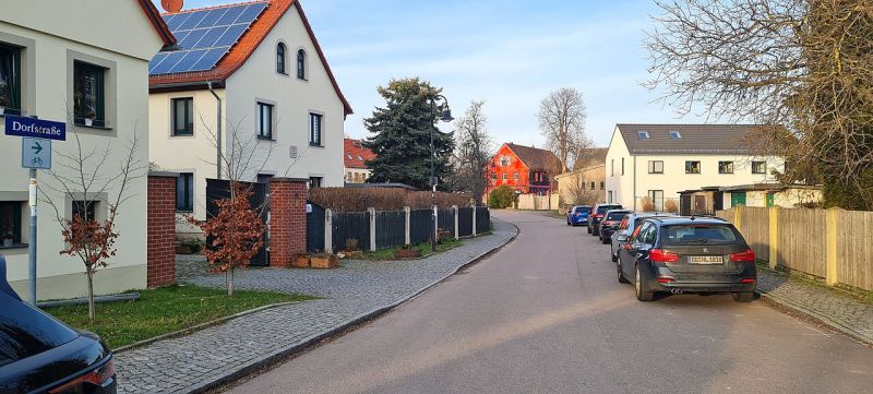 Dorfstraße im Dresdner Stadtteil Gohlis mit zweistöckigen Häusern und einigen Autos.