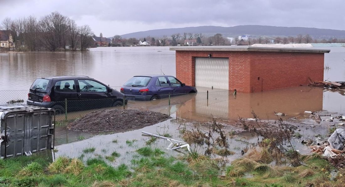 Eine Garage und zwei Autos stehen im wadentiefen Wasser, rundum ist Hochwasser, ganz vorn und ganz hinten ist Land.