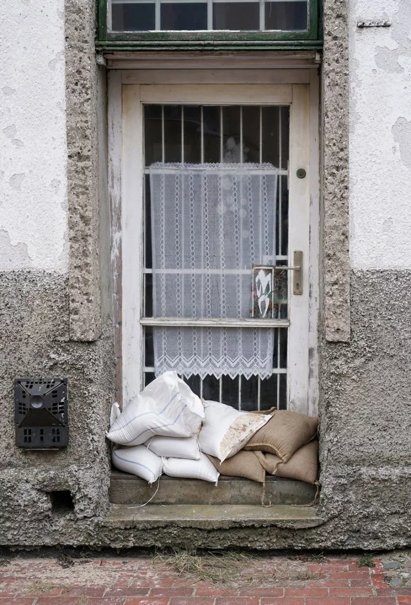 Sandsäcke liegen vor der Eingangstür eines sanierungsbedürftigen Hauses.
