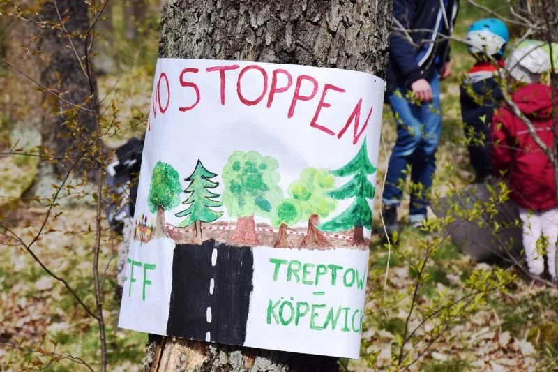 Ein handgestaltetes Plakat an einem Baum im Wald mit gemalten Waldbäumen und der Aufschrift: TVO stoppen - Fridays for Future Treptow-Köpenick.