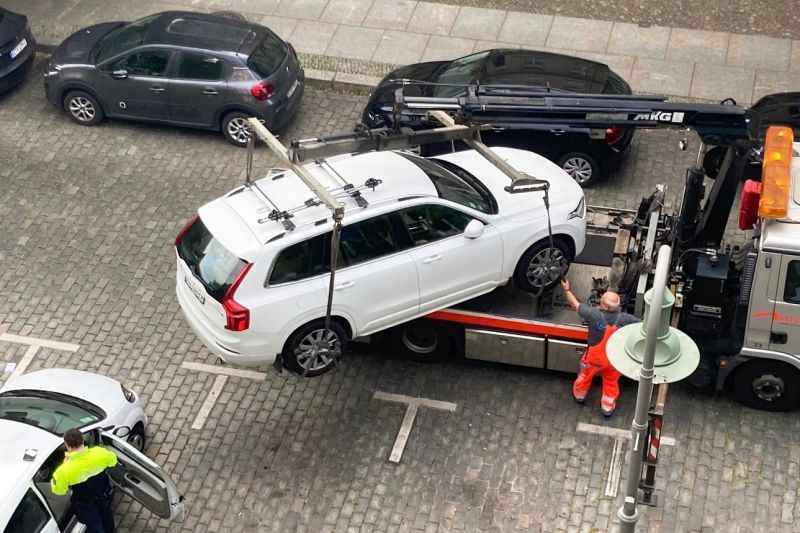 Ein weißer SUV wird auf einen Abschleppwagen geladen, er ist beinahe zu groß dafür.