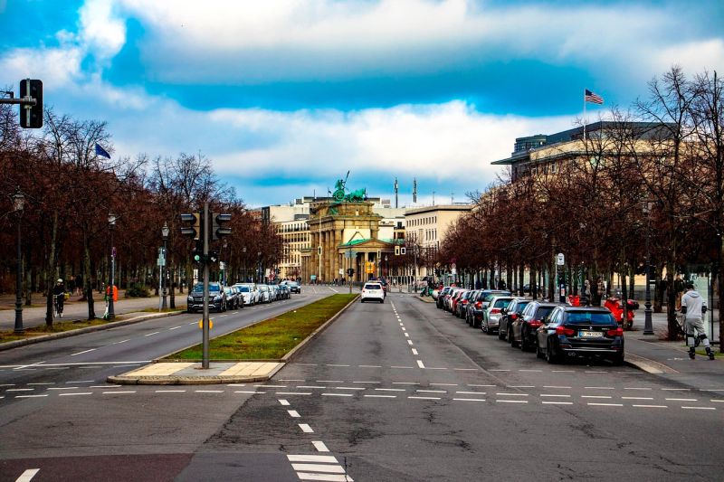 Auf einer Straße am Brandenburger Tor in Berlin fahren kaum Autos, während der Straßenrand vollgeparkt ist.