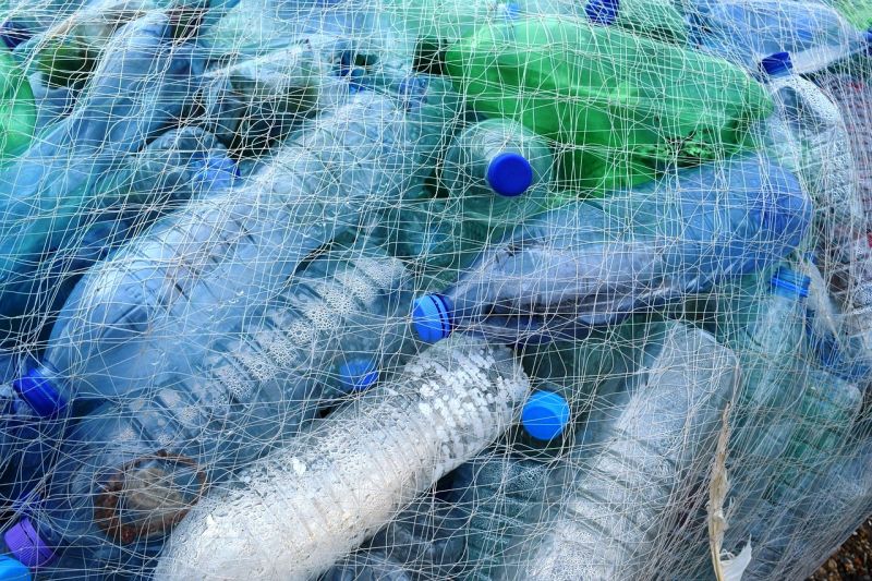 Viele Einweg-Wasserflaschen aus Plastik in einem Fischernetz.