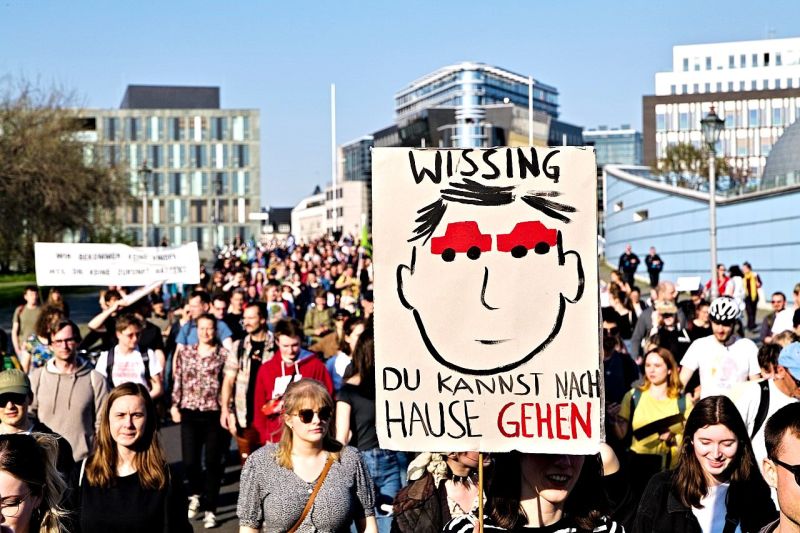 Demonstration von Fridays for Future mit einem Schild, auf dem ein Kopf mit Autos als Augen abgebildet ist und dem Satz: Wissing, du kannst nach Hause gehen.