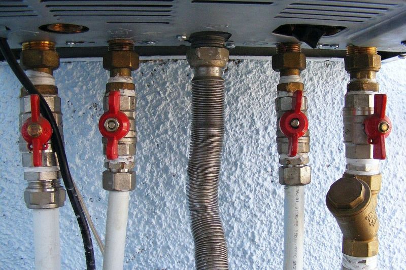 Fünf verschiedene Gasleitungen, fast alle mit rotem Absperrhahn, sind von unten an einen Gasheizofen angeschlossen.