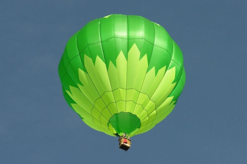 Ein grüner Heißluftballon entschwebt in den Himmel.