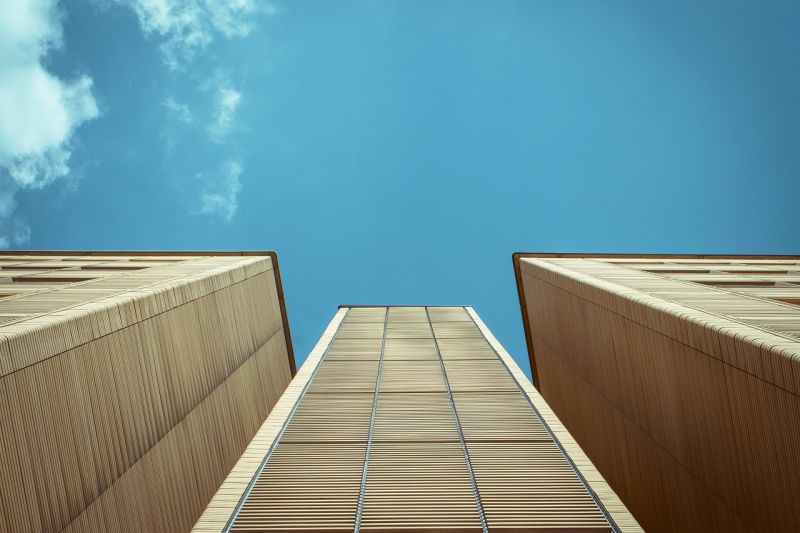 Fassaden von drei Beton-Hochhäusern, von unten gen Himmel betrachtet.