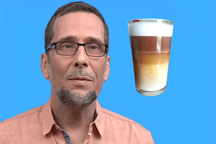 Aufmacherbild: Volker Quaschning im beigerosa Hemd vor blauem Hintergrund, hinter ihm ein Glas aufgeschäumter Milchkaffee.