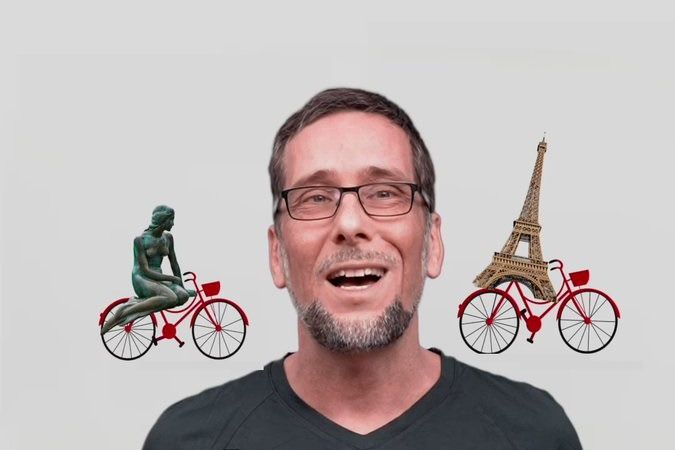 Volker Quaschning im schwarzen T-Shirt, hinter ihm Zeichnungen der kleinen Meerjungfrau und des Pariser Eiffelturms, die scheinbar Fahrrad fahren.