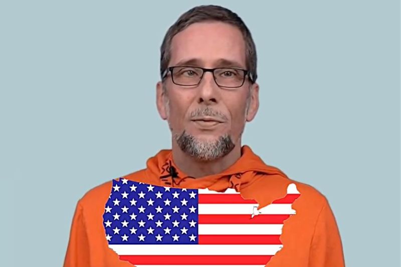 Aufmacherbild: Volker Quaschning im orangefarbenen Kapuzenpulli, vor ihm eine US-Flagge in der Form der USA.