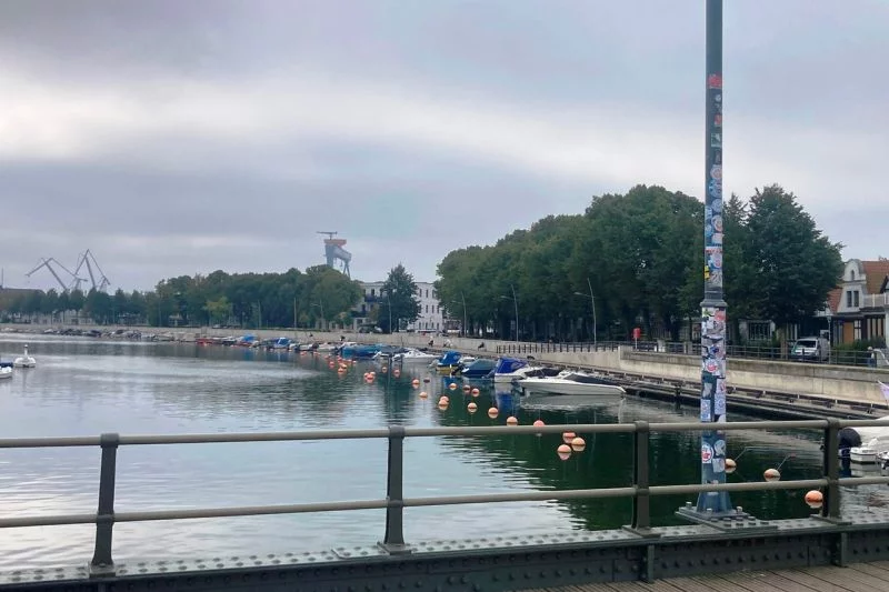Eine wenig auffällige Flutschutzwand aus Beton entlang eines Hafenbeckens.